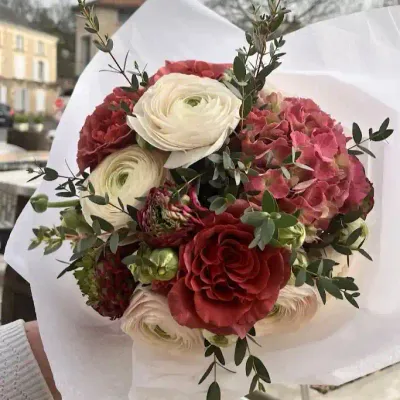 Bouquet de renoncules blanches et bordeaux, hortensia rouge ancien et eucalyptus dans un papier blanc
