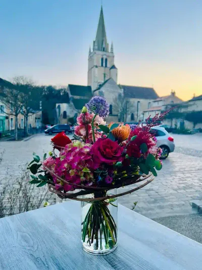 Bouquet en vase d'hortensia, roses rouges et allium sur une table, face à l'église de Saint-Benoît au crépuscule