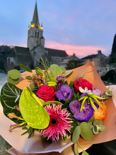 Bouquet coloré d'anthurium vert, gerbera rose, orchidées vanda et roses fuchsia devant l'église de Saint-Benoît au crépuscule