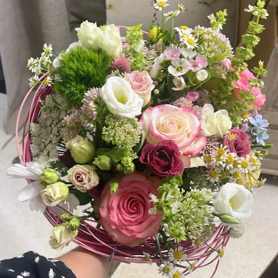 Bouquet rond dans une structure de fil rose : roses anciennes, lisianthus blancs, marguerites et ammi