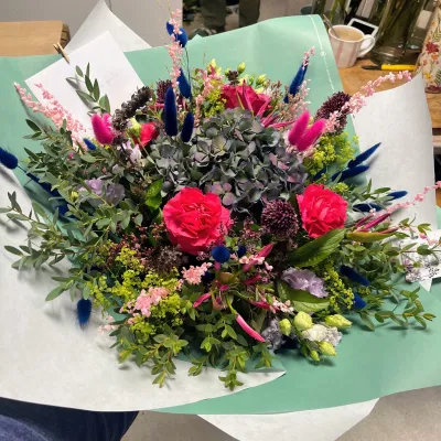 Grand bouquet d'hortensia, roses rouges, queues de lièvre bleues et feuillages, dans un papier vert d'eau