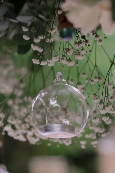 Boule en verre porte-bougie suspendue dans une pluie de gypsophile, décoration de mariage en extérieur