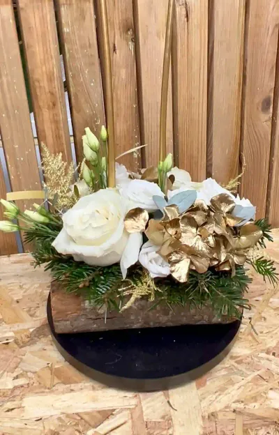 Composition de Noël sur rondin d'écorce : roses blanches, lisianthus, feuilles dorées et branches de sapin