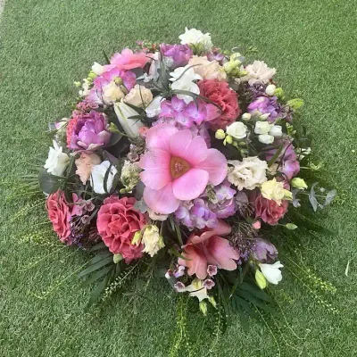 Coussin de deuil rond aux tons roses et mauves, lisianthus, œillets, alstroemerias et freesias blancs