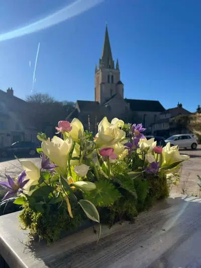 Composition horizontale sur mousse de lys crème, clématites violettes et tulipes, devant l'église de Saint-Benoît