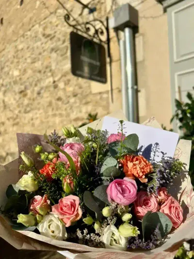 Bouquet de roses roses, œillets orange, lisianthus blancs et eucalyptus, sous l'enseigne de la boutique Herborium