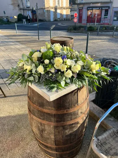 Dessus de cercueil en roses jaune pâle, lisianthus, eucalyptus et statice mauve, présenté sur un tonneau dehors