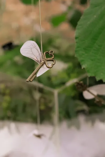 Détail de décoration de mariage : clé ancienne à ailes de papillon suspendue dans le feuillage
