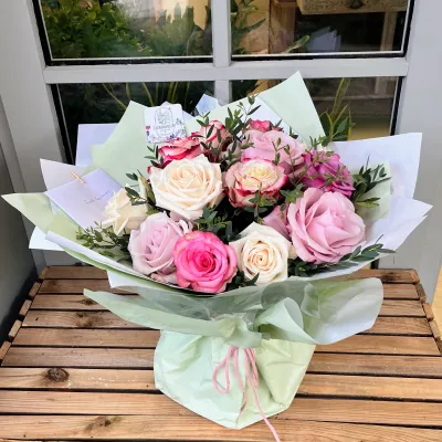 Bouquet de deuil à poser, roses roses et blanches, dans son emballage vert d'eau avec un nœud rose