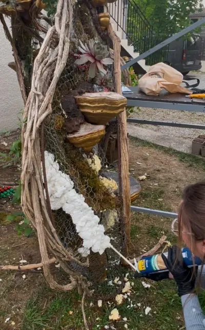Montage de la scénographie végétale : mousse expansive appliquée sur le grillage, entre lianes et champignons