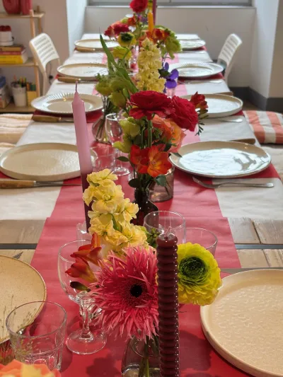 Table de réception au chemin de table fuchsia, soliflores de gerberas et de mufliers jaunes, bougies roses