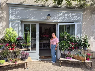 Léa Mahé sur le seuil de la boutique Herborium à Saint-Benoît, entourée de plantes et de fleurs en pots