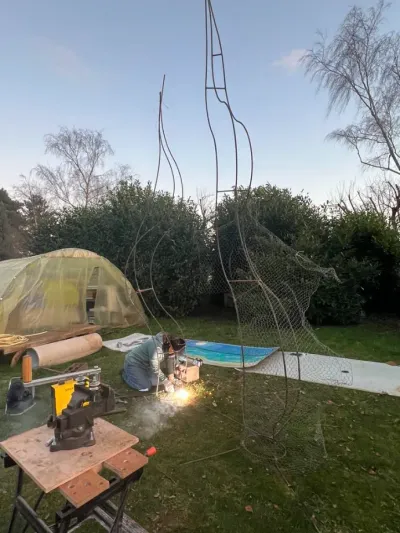 Soudure de l'armature en fer à béton de la scénographie végétale dans un jardin, étincelles et établi