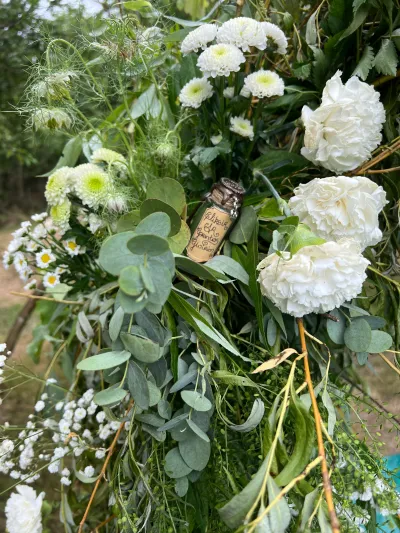 Détail d'arche de mariage : hortensias blancs, chrysanthèmes verts, eucalyptus, gypsophile et petite fiole en liège