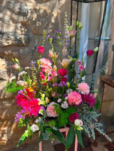 Devant de cercueil coloré de gerberas fuchsia, œillets roses et fleurs des champs, sur un support rose