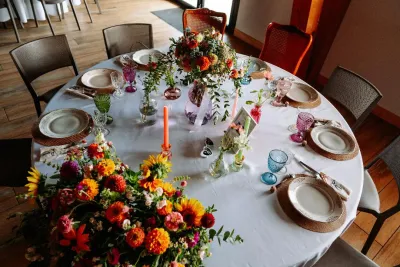Table ronde de mariage dressée, avec un centre de table de dahlias orange, de tournesols et de soliflores colorés