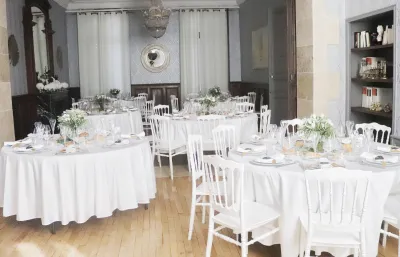 Salle de réception de mariage aux tables rondes nappées de blanc, chacune avec son centre de table de fleurs blanches