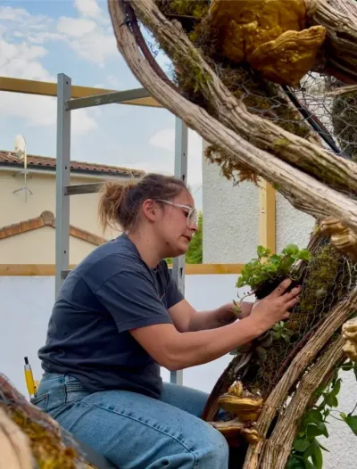 Mise en terre de plantes vivantes dans les poches de mousse de la scénographie végétale, sous l'abri de montage