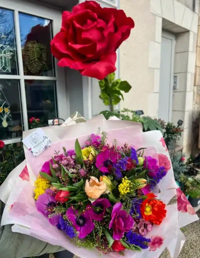 Bouquet de fleurs fraîches coloré avec une rose rouge centrale, création florale sur-mesure