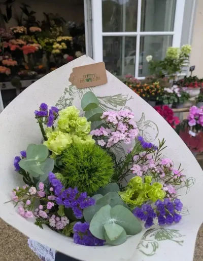 Bouquet rond dans les tons vert et violet préparé dans notre boutique de fleurs