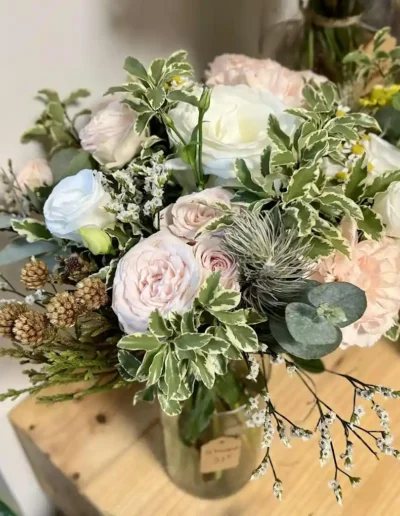 Centre de table doux et élégant avec des fleurs blanches et feuillages en vase