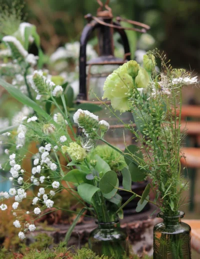 Décoration de table de mariage bohème avec vases anciens en verre, gypsophile et verdure à Saint-Benoît