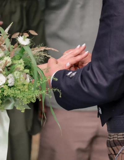 Gros plan sur les alliances des mariés tenant un bouquet champêtre vert et blanc sur Grand Poitiers