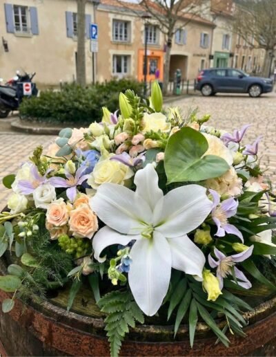 Gros plan sur une composition florale de condoléances avec un lys blanc central, disponible pour une livraison dans la Vienne
