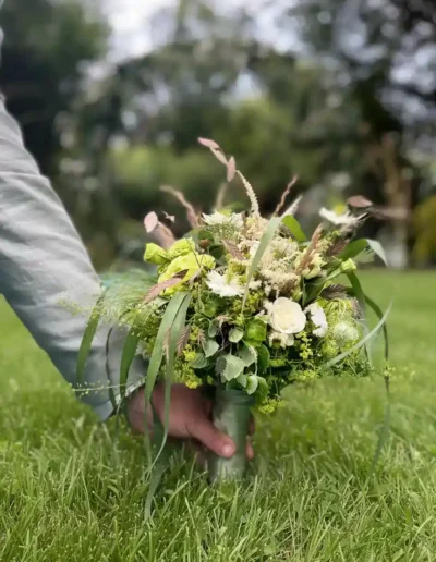 Petit bouquet pour demoiselle au style rond et verdoyant présenté en extérieur sur pelouse