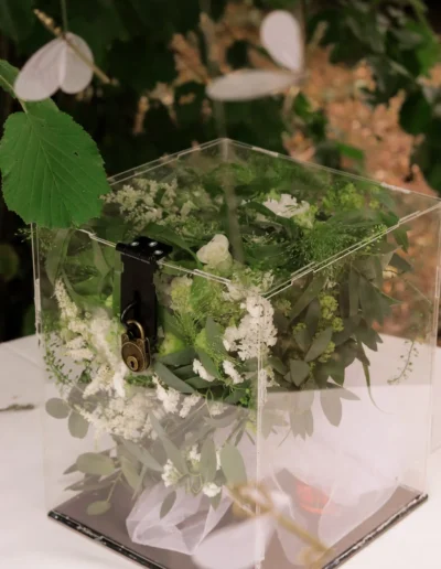 Urne de mariage transparente décorée de fleurs blanches et lierre, réalisée par notre atelier floral
