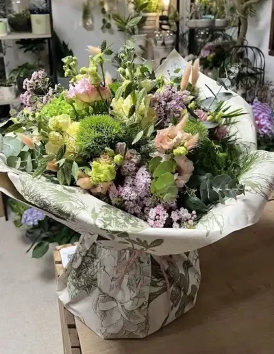 Bouquet de fleurs de deuil volumineux avec lisianthus roses et touches de vert enveloppe dans un papier floral