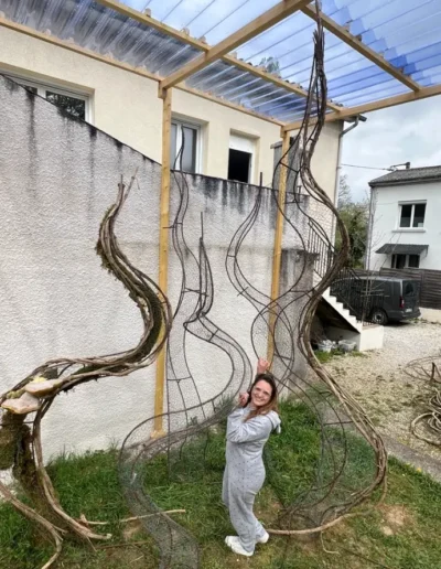 La scenographe vegetale assise sur un echafaudage pour installer les lianes et plantes sur la grande structure en bois