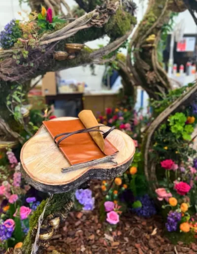 Livre dor pose sur une rondelle de bois au coeur de la scenographie vegetale fleurie pour un evenement